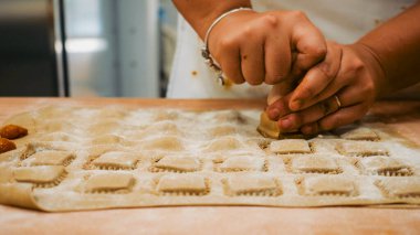 Lezzetli İtalyan mutfağı için ev yapımı ravioli hamuru kesme ve şekillendirme meydanlarını dikkatlice hazırlayan eller.