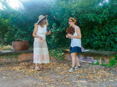 Yazın Giyinen İki Kadın Açık havada Yeşillik ve Doğal Güneş Işığı Altında Sohbet Ediyor