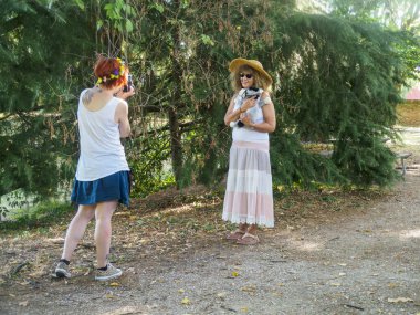 İki kadın arkadaş, yaz fotoshoot 'unun keyfini çıkarıyorlar. Parkta, doğal ışıklandırmayla birlikte güzel anları yakalıyorlar.