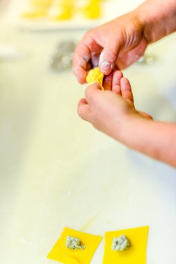 Eller, taze makarna hamuru ve enfes bir mutfak aktivitesi ile ev yapımı ravioli hazırlama sürecinde aktif olarak yer alıyor.