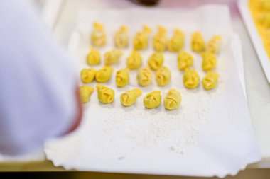 Taze İtalyan Ravioli Mantı Pişirme ve Yemek Fotoğrafçılığı Konsepti için un tozu içeren beyaz bir tepside hazır.