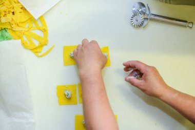 Yetenekli eller, otantik İtalyan mutfağı hazırlamak için taze ev yapımı ravioli dolgusu ve katlanmış makarna hamuru ustalıkla hazırlıyorlar.