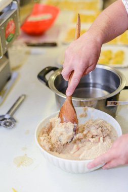 Eller hamuru beyaz bir kasede karıştırıyor. Mutfakta tahta bir kaşıkla.