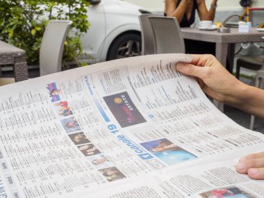 Crema, İtalya - 2 Temmuz 2025 Açık Kafe Masası 'nda Gazete okuyan Bulanık Araba Arkaplanı ve İnsanların İçeceklerin Tadını Çıkarması