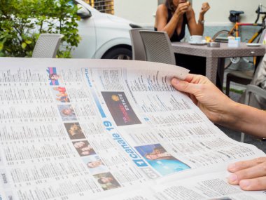 Crema, İtalya - 2 Temmuz 2025 Lombardy İtalya 'da açık bir kafede gazete okuyan biri sabah kahvesi ve pastasının tadını çıkarıyor.