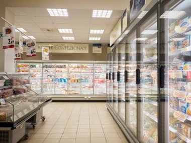 Lombardy, İtalya - 2 Temmuz 2025 İyi aydınlatılmış bir bakkal reyonu içinde çeşitli yiyecek ve içeceklerle dolu soğutulmuş vitrinler ve tüketiciler için içecekler