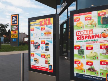 Lombardy, İtalya - 1 Ekim 2025 Aldi indirimli süpermarket girişinde, İtalya 'da gıda ve market ürünleri satışı bilgileri içeren tanıtım tanıtımı sergileniyor.