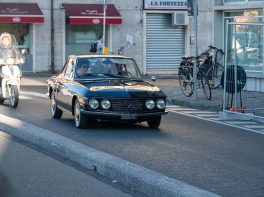 Pisa, İtalya - 16 Ekim 2025 Black Vintage Lancia Fulvia Coupe şehir yolunda gidiyor, binaları ve diğer araçları geçiyor, klasik Avrupa otomobillerini temsil ediyor