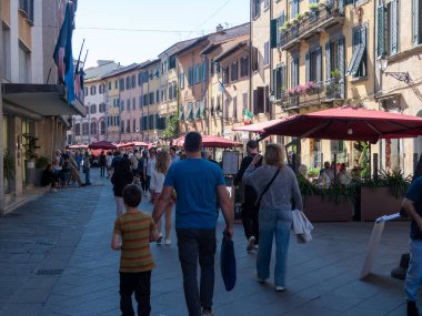 Pisa, İtalya - 16 Ekim 2025 Canlı bir caddedeki açık bir kafede yürüyen ve yemek yiyen insanlar. Güneşli Pisa 'da renkli cepheli tarihi binalar