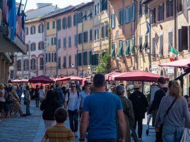 Pisa, İtalya - 16 Ekim 2025 Canlı bir caddedeki açık bir kafede yürüyen ve yemek yiyen insanlar. Güneşli Pisa 'da renkli cepheli tarihi binalar