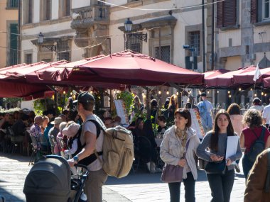 Pisa, İtalya - 16 Ekim 2025 Ziyaretçiler, Pisa, Tuscany, İtalya 'da zengin bir geçmişe sahip büyüleyici ve hareketli bir meydanda rahatça gezinen bir al fresco lokantasında yemek yiyorlar.