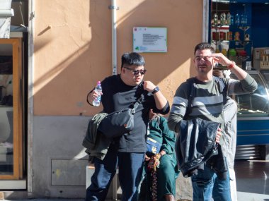 Pisa, İtalya - 16 Ekim 2025 Farklı bir grup insan Pisa, İtalya 'da güneşli bir sokakta yürüyor ve oturuyor, günlük şehir hayatı ve turizm sahnelerini yakalıyorlar