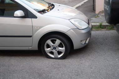 Cremona, İtalya - 2 Ekim 2025 Ford Fiesta gümüşü asfalt üzerine park edilmiş, ön tekerleği sönmüş, yol kenarı arızalı, lastik tamiri ya da acil durum yardımı gerekiyor.