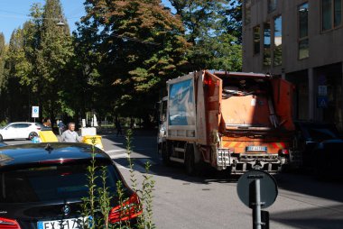 Cremona, İtalya - 2 Ekim 2025 Belediye temizlik işçileri kentsel atıkları yönetiyor. Çöp kamyonu çöp topluyor, çevre sorumluluğunu ve şehrin bakımını destekliyor.