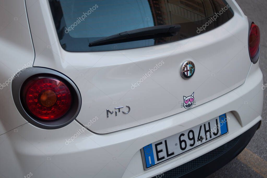 Cremona, Italy -October 2nd 2025 Rear view of an Alfa Romeo MiTo hatchback featuring an adorable cat sticker with heart eyes, a prominent badge, and an Italian license plate, parked elegantly on the s