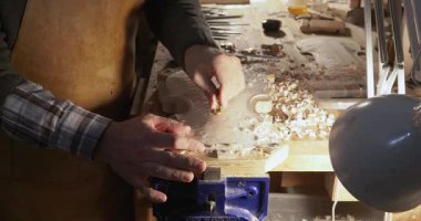 Keman plakası oyma, düzleştirme, ahşap şekillendirme üzerine yoğunlaşan usta kemancı, enstrümanlar ve ahşap ekipmanlarla çevrili, parlak ışıklandırılmış atölyede özel oyuklar ve araçlar kullanın