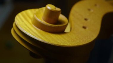 Ahşap çello parşömenini cilalamak, dikkatli fırça darbeleri ve klasik enstrümanların hassas detaylarıyla karmaşık işçiliğini ortaya koyuyor.