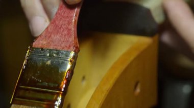 Geleneksel atölyede özel fırça kullanarak çello kısmını daha dikkatli cilalamak, karmaşık enstrüman işçiliğini vurgulamak.