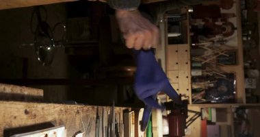 Atölyesinde yeni bir kemana vernik işlemine başlamadan önce eldiven takan kemancının dikey yavaş hareketi