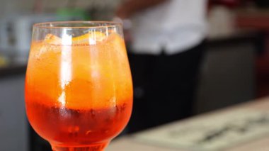 Buzlu soğuk spritz kokteyli, yanında aperatif kâsesi günbatımında moda kafede, ahşap bar tezgahında dinleniyor.