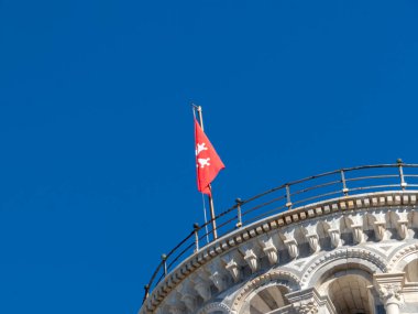 Pisa, Toskana - 16 Ekim 2025 İkonik Eğik Pisa Kulesi Piazza dei Miracoli Toskana İtalya 'sında Mavi Gök Altında Kızıl Bayrak Dalgalanıyor