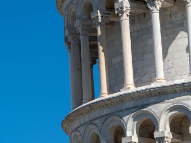 Pisa, İtalya - 16 Ekim 2025 Pisa, İtalya 'daki ikonik Eğik Kule' ye yakın çekim, açık bir gökyüzüne karşı tarihi mermer sütunlar ve kemerler sergileniyor