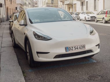 Cremona, İtalya 14 Ağustos 2025. Beyaz bir Tesla Model Y Avrupa 'nın bir yan sokağına park edilmiş ve lüks tasarımı ve modern özellikleri sergilenmektedir.