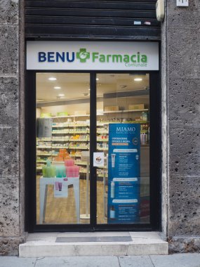 Cremona, İtalya 13 Ağustos 2025 Cremona, Lombardiya 'daki Benu Farmacia Comunale mağazasında davetkar cam kapılar ardında çeşitli sağlık ürünleri ve kozmetik ürünleri sergilenmektedir.