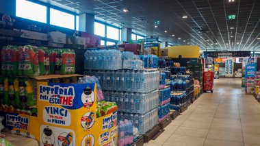 Cremona, İtalya - 15 Ağustos 2025 'te aydınlık, modern bir süpermarkette raflarda ve karton tezgahlarda sergilenen çeşitli şişe su ve içecek ürünleri sergilendi.
