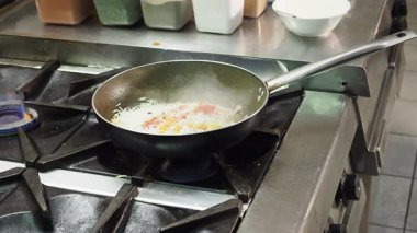 Profesyonel aşçı otantik Hint mutfağı yapıyor. Profesyonel sobanın üzerinde restoranın mutfak tavasında sotelenirken özenle aromatik baharatlar ve taze malzemeler ekliyor.