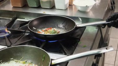 Profesyonel usta aşçı geleneksel Hint mutfağını yaratıyor, ticari mutfak ortamında yemek pişirirken ustalıkla baharat ve karışımı karışımı karışımı şeyler yapıyor.