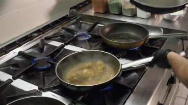 Profesyonel şef mutfak üniforması giyiyor ve koruyucu siyah eldivenler giyiyor geleneksel Hint mutfağını hazırlıyor, profesyonel mutfak tavasında yoğun mavi alev sobasıyla kaynayan malzemeler.