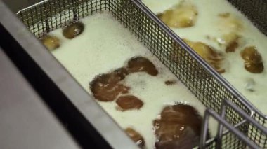 Profesyonel şef geleneksel Hint Pakora 'sını hazırlıyor, onları kızartma sepetinde kızgın yağda kızartıyor, yemek pişirmeyi ve çıtır çıtır dokumayı garantiliyor.