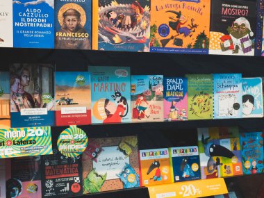Cremona, İtalya 27 Eylül 2025 İtalyan kitapevi raflarında renkli kapaklı ve indirimli etiketli çocuk edebiyatı da dahil olmak üzere çok çeşitli kitaplar sergileniyor.