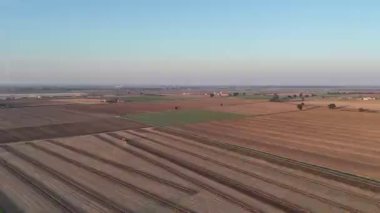 İtalya 'daki Po Vadisi' nin tarımsal manzarası, güzel ve sıcak bir günbatımında açık bir gökyüzünün altında bir traktör tarlayı sürüyor.