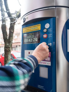Sezana, Slovenya - 22 Kasım 2025 Slovenya 'da Mevlana, Slovenya' da modern dijital parkmetreyi işleten kişi, park ücretini ödemek için düğmelere basıyor, kentsel kolaylık ve günlük konforu gösteriyor
