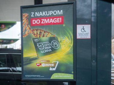 Sezana, Slovenya - 22 Kasım 2025 MOL ücretsiz yakıt istasyonu tanıtımı ve MoVE uygulaması pompada yardıma ihtiyacı olan engelli müşterilere yardım sağlayan bir erişim tabelasıyla sergilendi