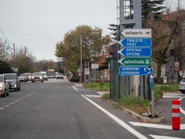 Trieste, İtalya - 21 Kasım 2025 İtalya sınırı yakınlarındaki bir yolda ilerleyen trafik, çok yönlü mavi ve yeşil yol işaretleri ile Trieste gibi varış noktalarını gösteriyor,