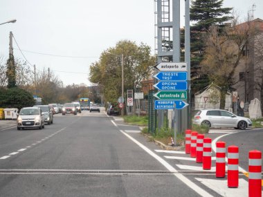 Trieste, İtalya - 21 Kasım 2025 Trieste, otoyol ve diğer mekanları gösteren işaretler yoğun bir yolun kenarında duruyor.
