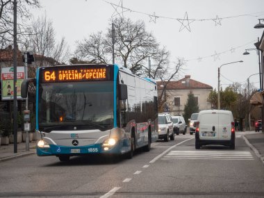Trieste, İtalya - 21 Kasım 2025 64. karayoluna giden halk otobüsü Piazza Tommaseo ve Opicina 'ya gidiyor, kalabalık bir caddede arabalar ve kamyonlarla seyahat ediyor, günlük banliyö ve sınır geçişini temsil ediyor.