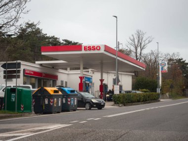 Trieste, İtalya - 21 Kasım 2025 Slovenya 'nın Sezana kentinde bir yol kenarında yer alan Esso benzinliği, yakıt pompaları, bir dükkan ve geri dönüşüm kutularının yer aldığı,