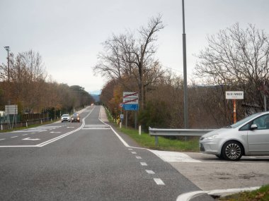 Trieste, İtalya - 21 Kasım 2025 Slovenya ve İtalya 'yı yol kenarındaki bir kavşakta birbirine bağlayan açık yol, trafik bulutlu bir sonbahar gökyüzü altında ilerlerken bekleyen otomobil, sınır ötesi seyahatin vurgulandığını vurguladı