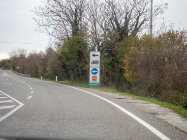 Trieste, İtalya - 21 Kasım 2025 Virajlı asfalt yolun kenarında durmakta, Venezuela yönünü, sınır geçişini ve uluslararası seyahati temsil etmektedir.