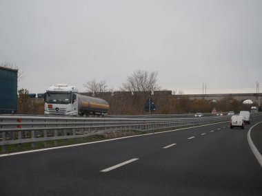 Friuli, İtalya 21 Kasım 2025 Mercedes Benz tankeri İtalya 'nın A4 otoyolunda bulutlu bir gökyüzü altında yakıt taşıyor, arka planda viyadük, hareket ve hız yakalandı