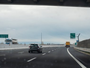 Friuli, İtalya 21 Kasım 2025 Latisana kavşağına yaklaşan A4 otoyolu üzerindeki araç bulutlu gri gökyüzü altında Milano ve Venezia 'ya yönelik yön işaretleriyle