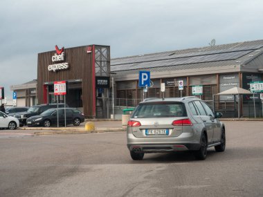 Friuli, İtalya 21 Kasım 2025 Gri steyşın vagon servis istasyonunun otoparkından Chef Express restoranı, güneş panelleri, İtalya 'da bulutlu gökyüzü ile geçiyor.