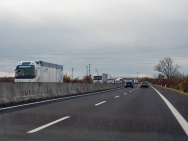 Friuli, İtalya 21 Kasım 2025 A4 otoyolu bulutlu bir gökyüzü altında çok şeritli araç ve kamyon trafiği ile ulaşım altyapısı ve hareketlerini vurguluyor