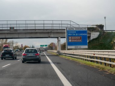 Friuli, İtalya 21 Kasım 2025 İtalya otoyol trafiğinin ortasında Cessalto, Ceggia, Motta di Livenza, Oderzo ve Eraclea için A4 otostrada çıkış tabelaları üzerinde araçlar