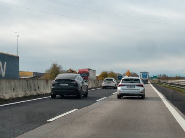 Friuli, İtalya 21 Kasım 2025 Tesla Model Y elektrik ve Skoda Octavia 'nın bulutlu bir gökyüzünün altında, hareket halindeki araç ve kamyonlarla çevrili olarak İtalya' nın A4 otoyolunda yan yana sürüşleri görülüyor.