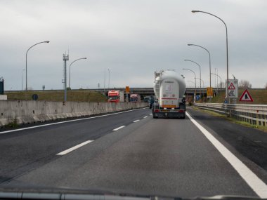 Friuli, İtalya 21 Kasım 2025 Yollarda seyahat eden araçlar, önplanda bir tanker kamyonu, bulutlu bir gökyüzünün altında diğer kamyonlar ve sokak lambaları